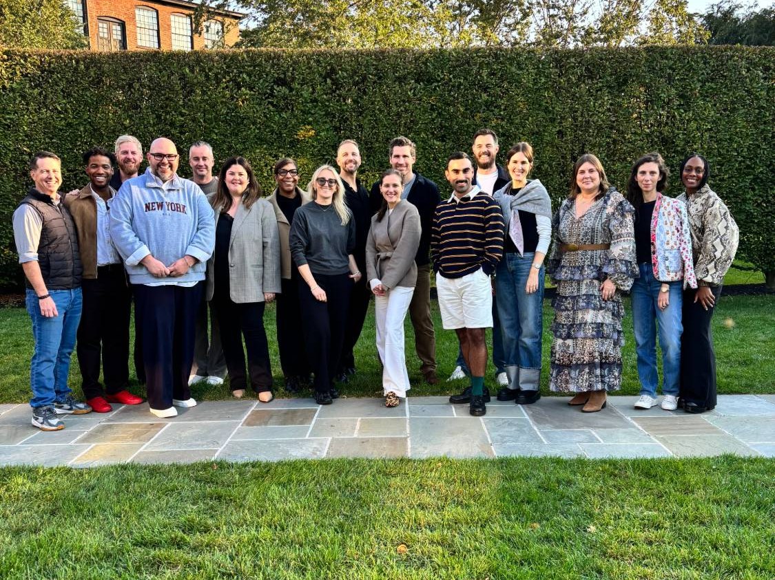 Shem Hatfield standing at the far left of a group of workshop participants posed in a garden in front of a tall hedge in Beacon, New York